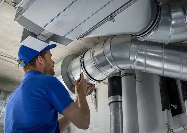 An HVAC technician inspecting commercial ventilation ductwork